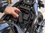 Compact petZeye PZE100-L GPS tracker being installed beneath a motorcycle seat